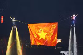 表演者在同奈河上进行高空升旗表演，越南国旗迎风飘扬。图自 越通社