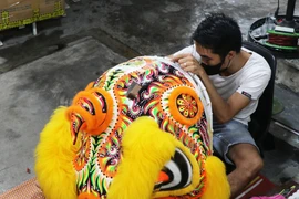居住在顺化市富春坊长兴道的张如任先生正在加紧完成一只大型舞狮狮子头作品。图自 越通社