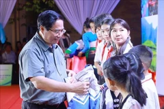 范明政总理向学生们赠送礼物。图自越通社