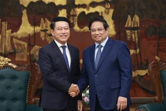 越南政府总理范明政与老挝副总理、人民革命党中央企业改革委员会主任沙伦塞·贡马西合影。越通社