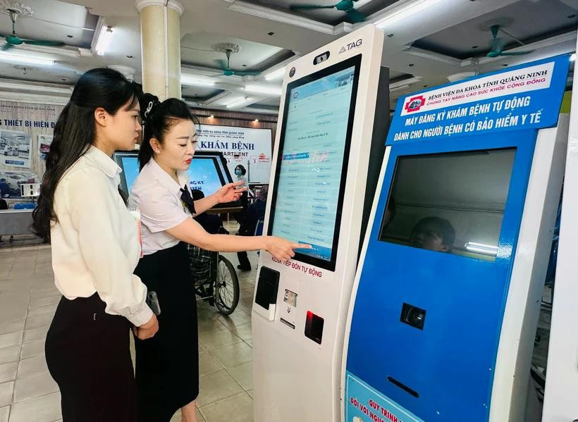 广宁省综合医院医务人员指导民众使用自助挂号机。图自Vietnam+