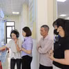 茂阿乡公共行政服务中心干部指导群众在AI Kiosk上进行操作。图片来源：越通社
