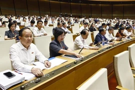 越南国会代表按下表决器表决通过关于2013年《宪法》若干条款修改补充的决议。图自越通社