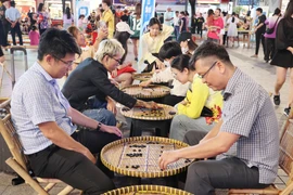 游客体验民间游戏。图自越通社