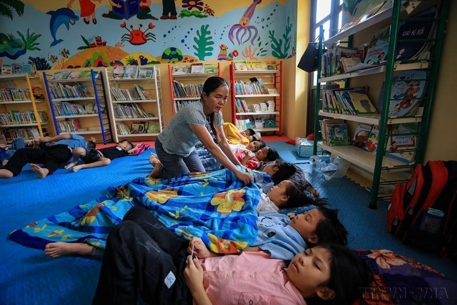 越南通过以人为本、具有人文关怀的政策措施,提高人口素质。图中:和平省山富学校的一名老师照顾让村的学生。图自越通社