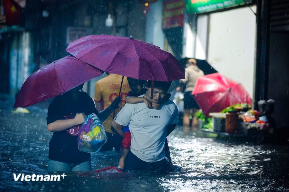 河内市市民在“水中街道”艰难接孩子、买菜。图自越通社