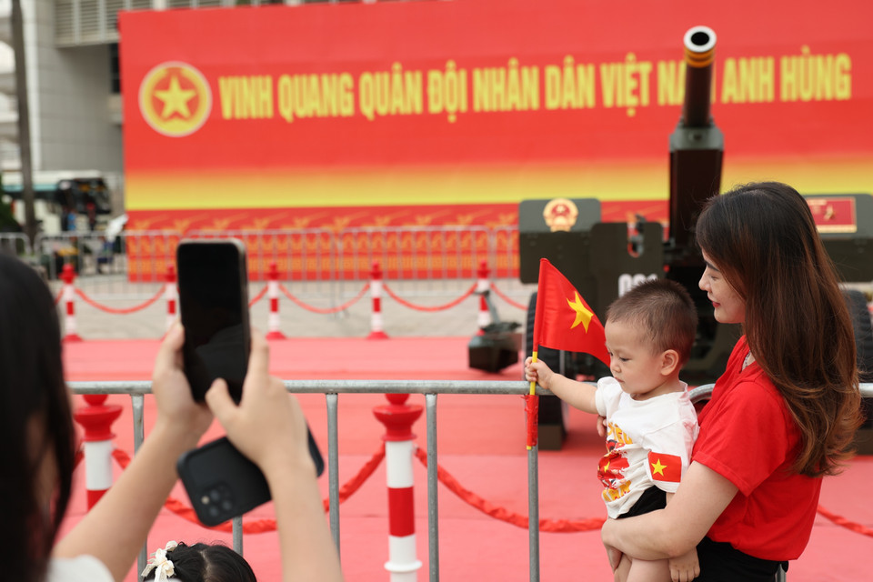 孩子们在父母的带领下，手持国旗与礼炮合影。图自越通社