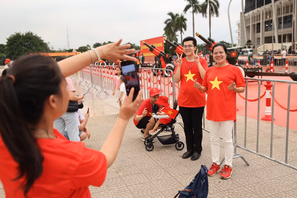 人们兴奋地在美亭体育场与礼炮合影留念。图自越通社