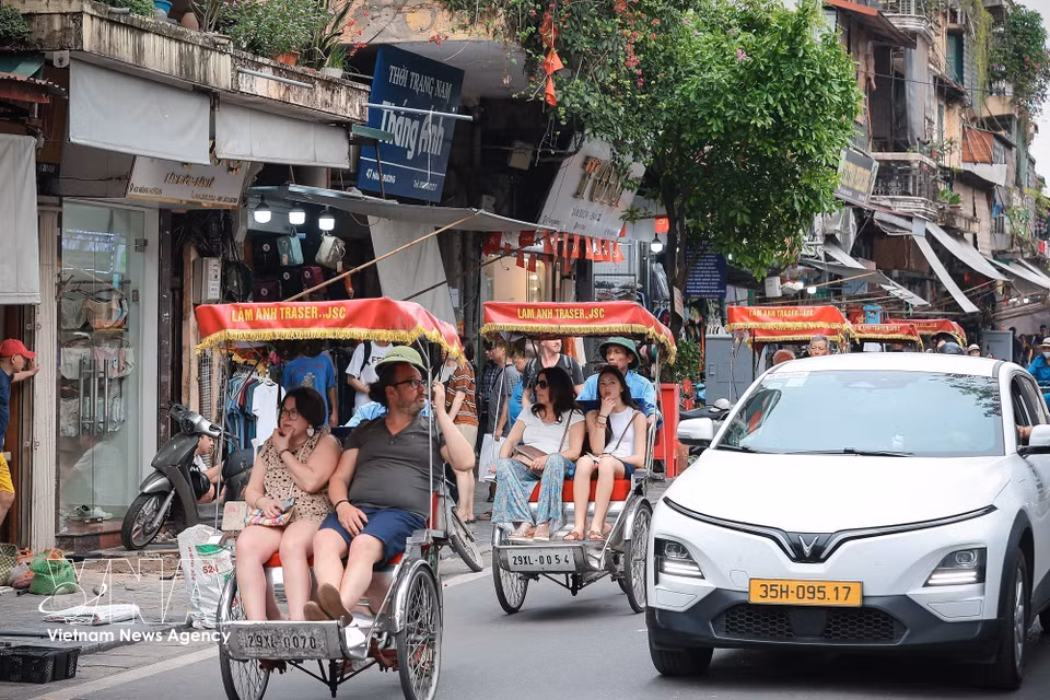 游客乘坐三轮车游览河内古街，在2026年雄王祭祖日假期感受首都独特的城市风貌与历史建筑。图自越通社