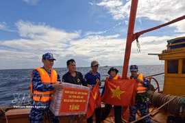 海警二区司令部的干部战士向渔民赠送国旗和慰问品，鼓励他们安心出海、扎根海上作业，严格遵守水产捕捞相关规定。图自越通社