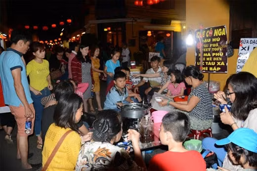 游客在会安古城玲珑灯光下品尝当地美食。（图片来源：人民军队报）