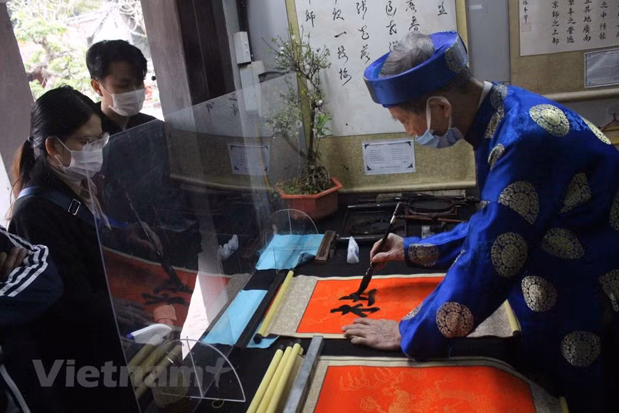 这些大学生刚从老家返回河内。他们选择参观河内各旅游景点，并在文庙求字。在新春佳节的喜庆气氛中，奥黛的五颜六色、红色的宣纸和黑墨的笔画构成一副美丽的画面。拜字、迎字、玩文字、求字、送字是越南人从早就有的优良传统。其中，拜字和迎字是针对皇帝手写的字；而玩文字、求字和送字则是老百姓每逢春节的习俗。图自Vietnam+