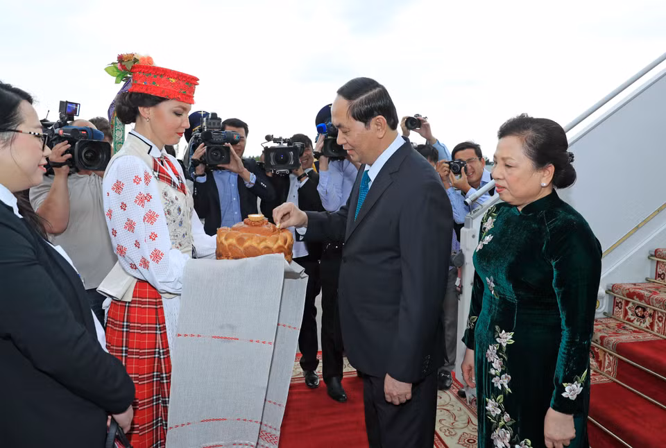 身穿传统服饰的白俄罗斯姑娘按照当地迎接最尊贵客人的礼节向陈大光主席和夫人献上象征热情友好的面包和盐。（图片来源：越通社）