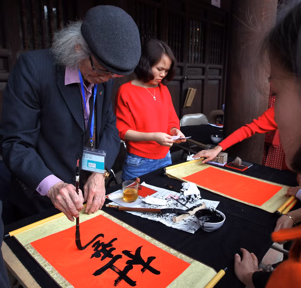 年轻游客请图翁替人写字，希望在新一年里安康、旺盛。越通社记者 国庆 摄