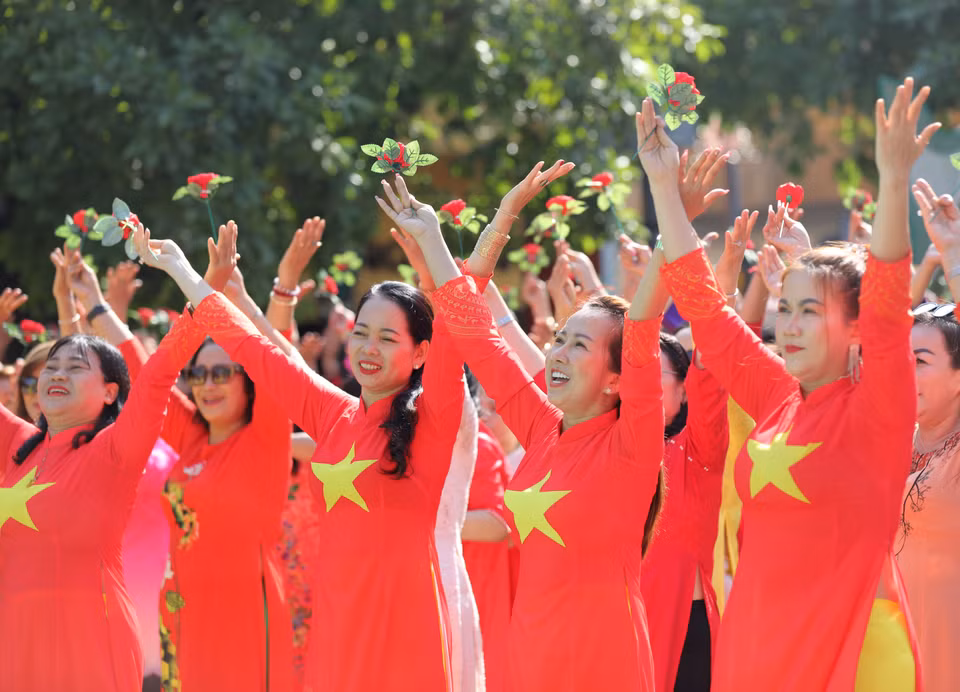 身着国旗红并印有国旗图案的奥黛的众多胡志明市妇女参加奥黛同台走秀。图自 越通社《越南画报》