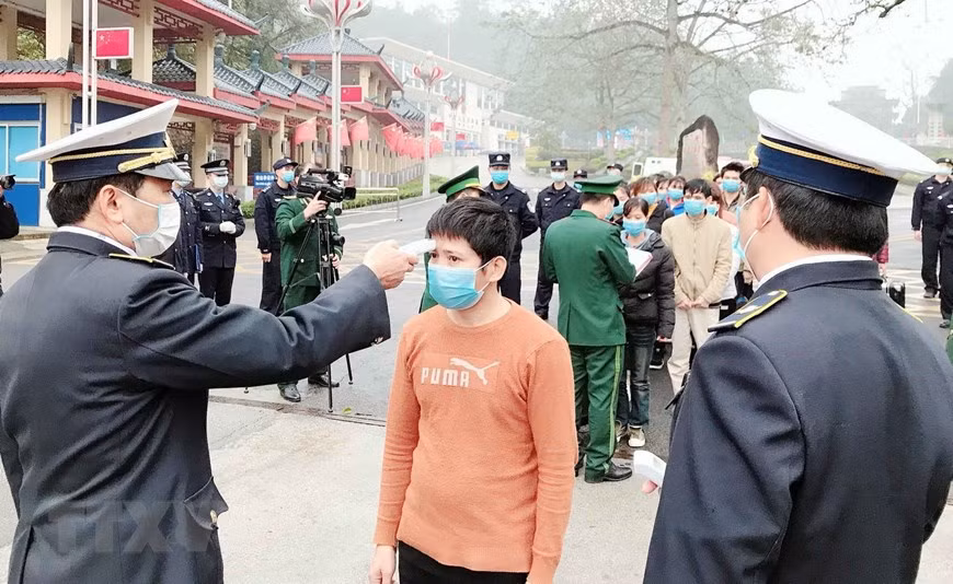 在各国际口岸，在办理入境越南的手续之前，医务人员给旅客测量体温。（图自越通社）