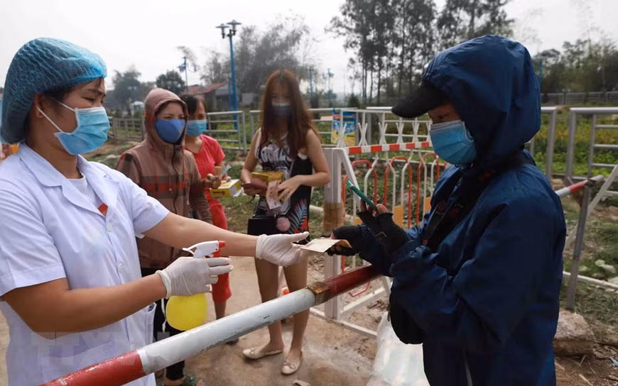 在山雷乡一号疫情监控检查点，在签收货物结算之前，医务人员对钱币进行消毒。（越通社记者黄雄 摄）