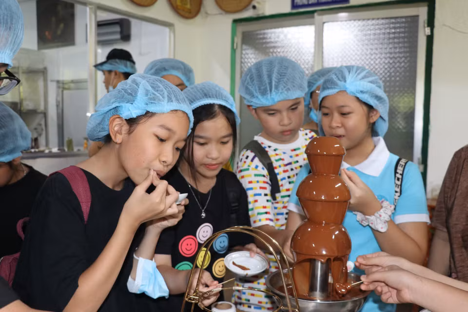 小朋友们品尝在𢄂𥺊春伦可可有限公司生产的生鲜巧克力。图自越通社