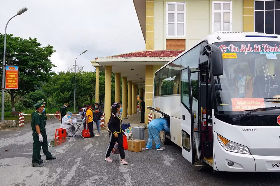 越南和老挝公民和留学生在西庄国际口岸办理出入境手续之前需要进行健康申报、佩戴口罩并测量体温。 越通社记者 潘俊英 摄 