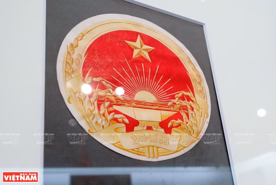 裴庄灼画家的一幅国徽草图：其上面画着红旗上面的金星、日出光芒、一条丝绸包围着稻花和象征着农业的铁砧。图自 越通社