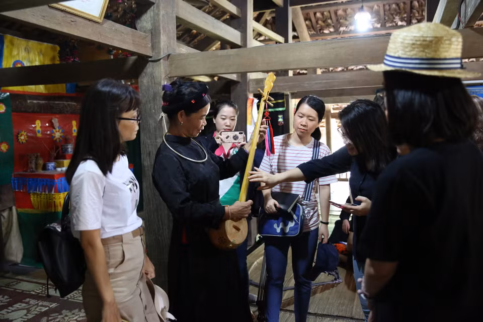 游客们通过岱依族传统乐器天曲更加深入了解岱依族的文化特色。图自越通社 