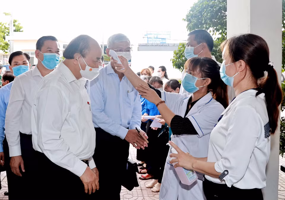 在与代表霍门县各组织、企业和忠政乡选民接触之前，专业人员为阮春福主席量体温。图自 越通社