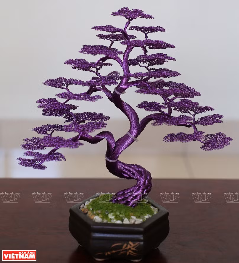 在范文营的灵巧双手下，由铜线制成的一棵棵树开始成型。图自越通社