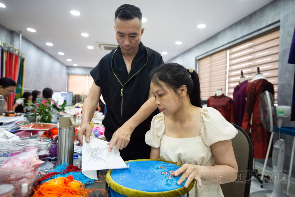 设计师杜郑淮南同员工就布料上的图案刺绣流程进行交谈。图自越南画报