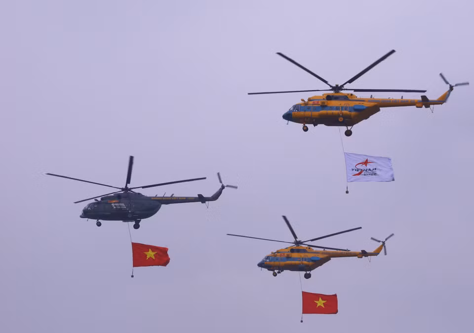 越南人民军空军第916团的Mi系列直升机挂着越南国旗和2022年国际防务展会旗帜在空中飞行表演。图自 越通社