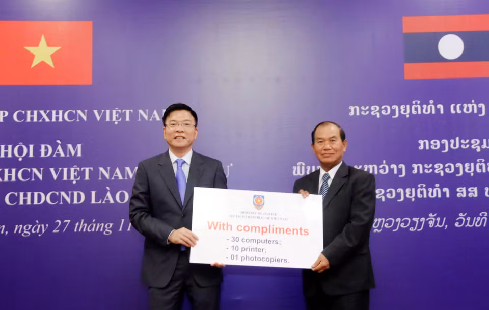 越南司法部长黎成龙向老挝司法部长塞西•桑迪冯转交越南司法部的礼物。（图片来源：越通社）