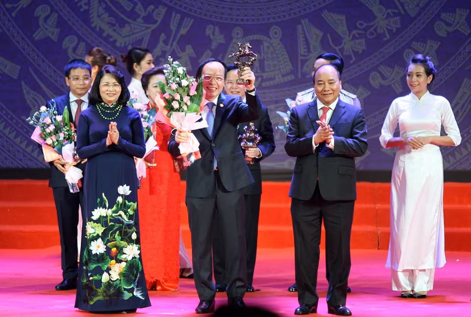 越南国家主席邓氏玉盛和政府总理阮春福向典范企业家授予喠圣奖杯。（图片来源：越通社-VNA）