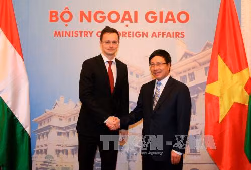  越南政府副总理兼外长范平明迎接彼得·西亚尔托部长。（图片来源：越通社）