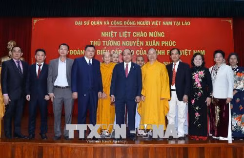 阮春福与越南驻老挝大使馆工作人员和旅老越南人代表​合影。越通社记者 统一 摄