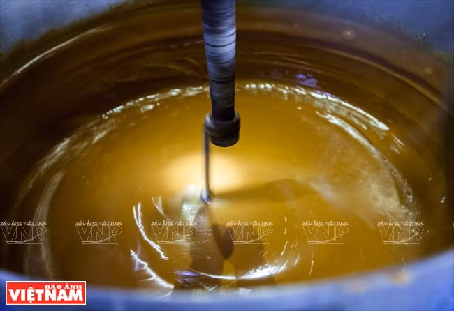 一直搅拌至糖汁慢慢凝成浓稠的深黄色液体即可。（图片来源：越南画报）