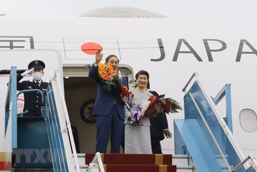 日本首相菅义伟与夫人登上飞机离开河内。图自越通社
