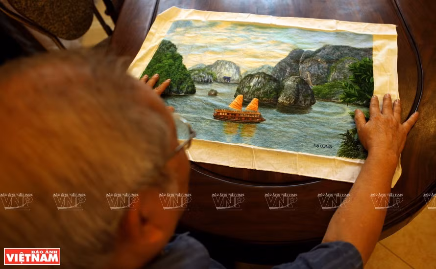 橘洞村艺人向观众介绍一幅精美的《下龙湾》手工刺绣画。越通社记者 郑部 摄