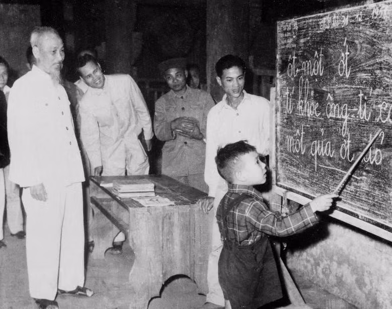  1958年12月31日，胡主席在拜访河内市行碳街观察一一个儿童练习拼字。