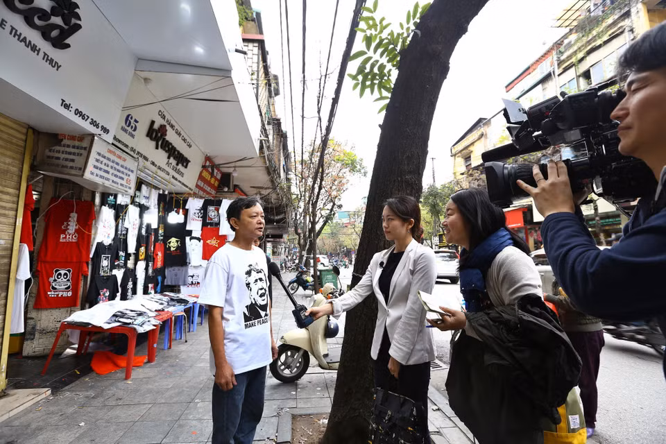 售卖印有特朗普与金正恩图案的T恤的店主接受国际媒体的采访。 图自越通社