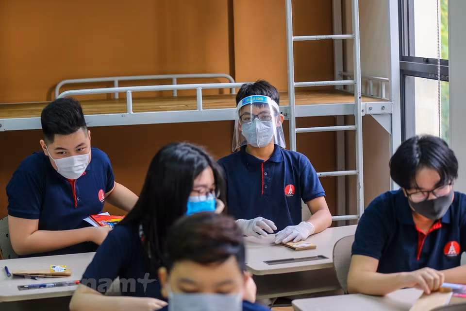 除了佩戴口罩之外，有的同学还佩戴防飞沫帽子。家长们都嘱咐自己的孩子下课后不要与同学们聚集。越通社记者 明山 摄