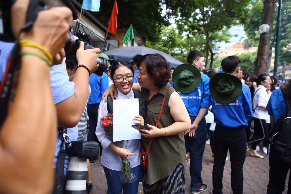 一名学生与校外的父母说着这次考试题目的难度。（图片来源：越通社）