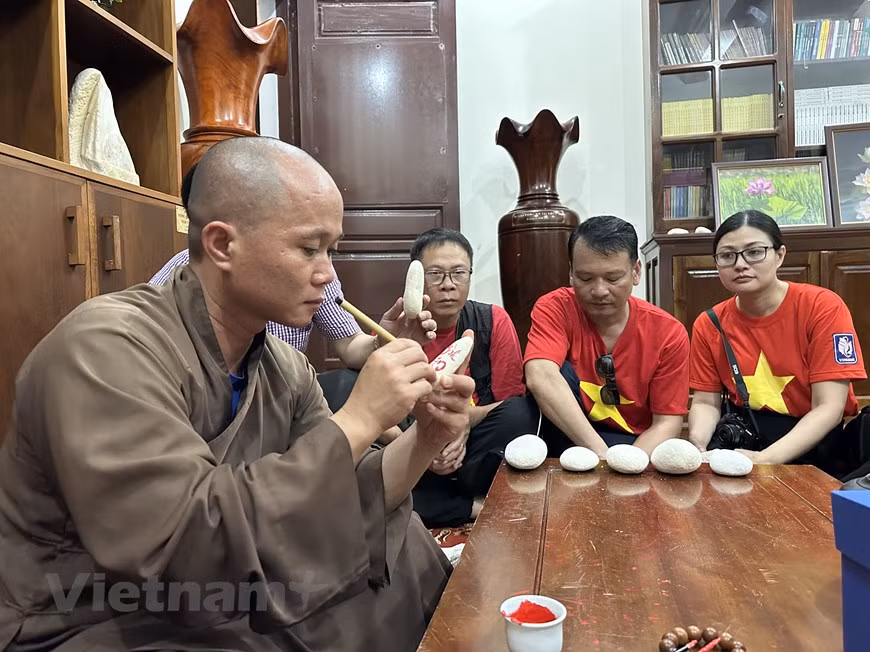 大长沙寺住持释觉义大德为探望长沙群岛的游客送字。图自Vietnam+