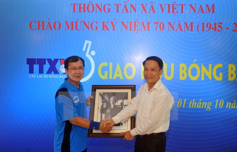 越通社社长阮德利向越通社乒乓球俱乐部赠送胡伯伯锻炼身体照片。（图片来源：越通社）