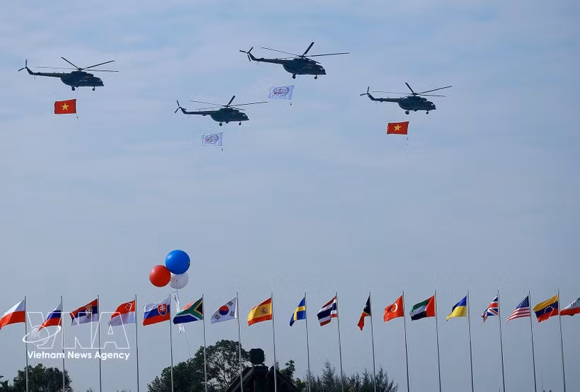 载有国旗的直升机在2024年越南国际防务展开幕式上进行飞行表演。图自越通社