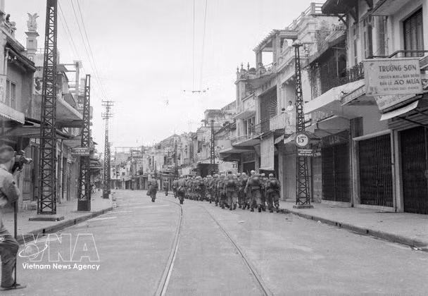 根据《日内瓦协定》有关条款，法军须在80天内撤离河内。1954年10月8日，法军举行降旗仪式；10月9日开始撤离河内。法军撤离一处，越南人民军便接管一处。当日16时30分，法军全部撤过龙边桥，越南人民军全面接管河内。图为：1954年10月9日下午，法军步兵部队悄然穿过行桃街（Hàng Đào），经龙边桥撤往海防。图自 越通社