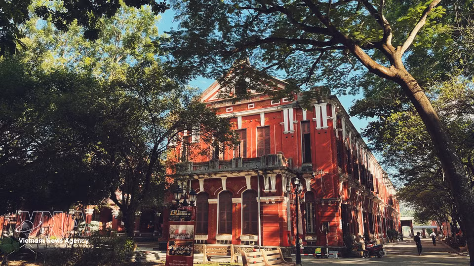 学校具有鲜明的印度支那建筑风格，温暖沉稳的红色外墙与拱形门窗格外醒目。图自 越通社