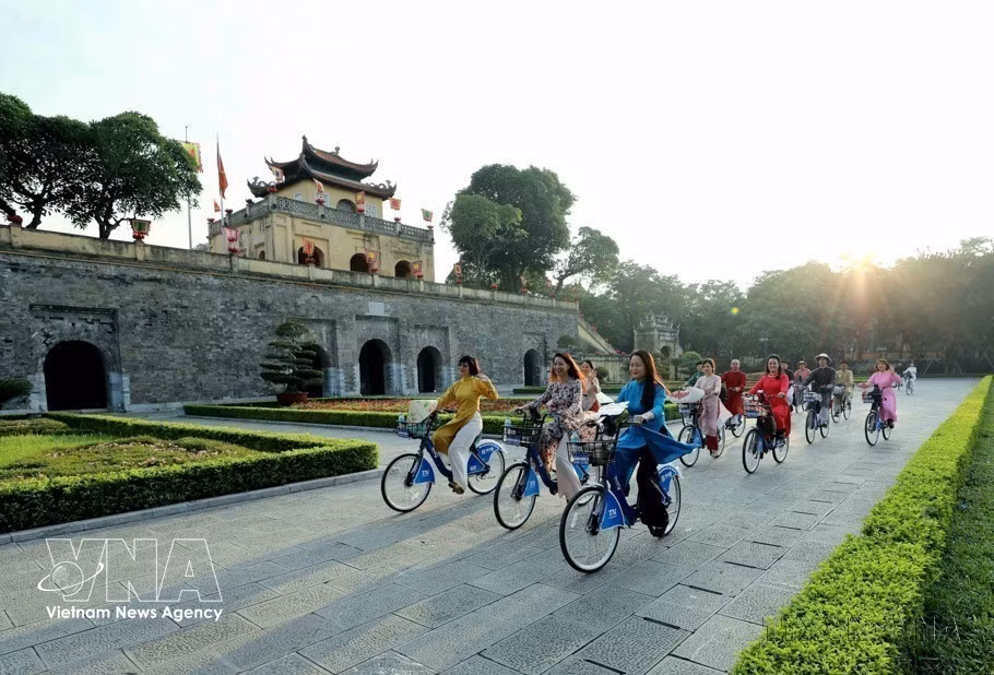 在国际友人眼中，河内是一座充满活力、蓬勃发展，同时又保留着独特传统风貌的城市。图为：2023年，在首届“奥黛连接河内旅游与遗产”活动中，身着奥黛的河内女性骑自行车穿行于各处遗产景点。图自 越通社
