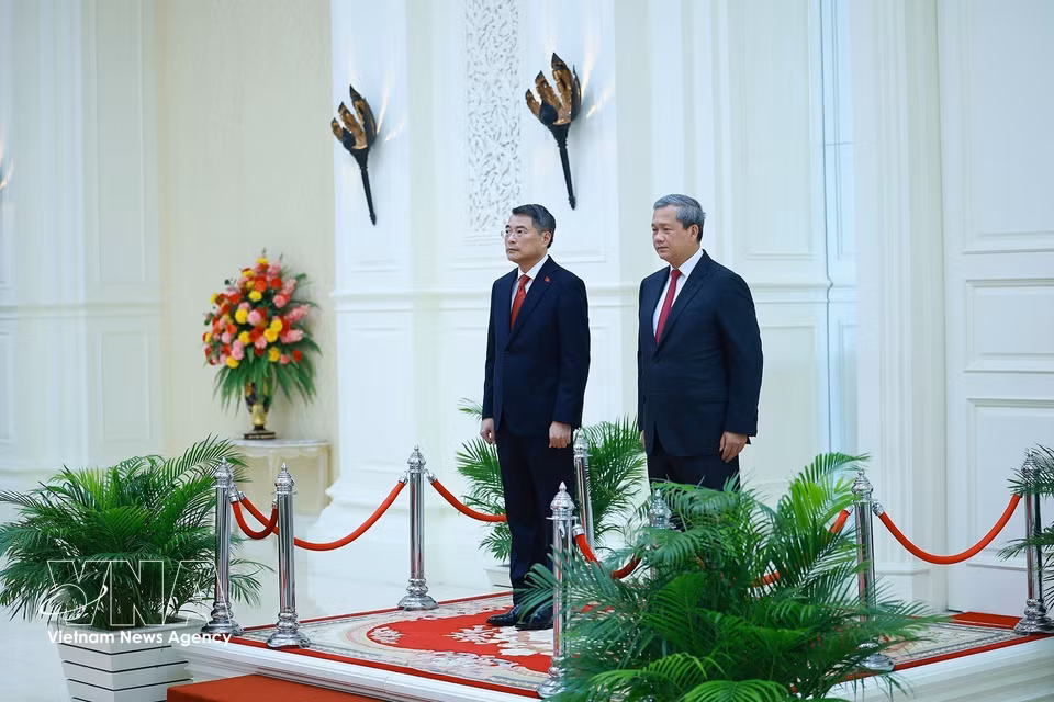 越南政府总理黎明兴与柬埔寨首相洪玛奈登上检阅台，聆听军乐队奏响两国国歌。图自 越通社