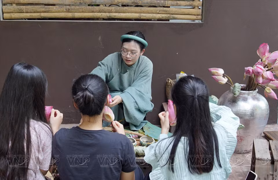 参观者品尝百艺坊的河内莲花茶。图自越通社