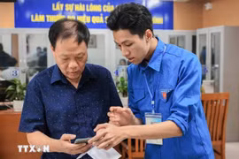 团员指导群众在智能手机上使用和申报各项网上公共服务。图自越通社