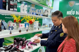 国内市场管理与发展局工作人员向消费者指导如何辨别真伪化妆品。图自越通社